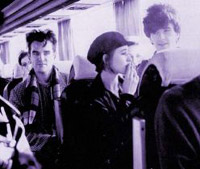 Angie Brown fuma um cigarro, ao lado de Johnny, dentro do ônibus da banda 
